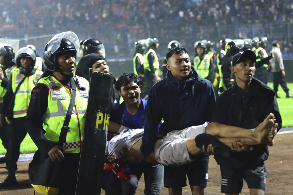 مشجعو كرة القدم يحملون رجلاً مصابًا في الملعب